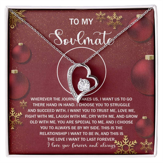 The Soulmate-By My Side 2 - Forever Love Necklace boasts a silver heart shape, beautifully accented with a central CZ crystal, all presented in a charming gift box. The backdrop highlights a festive red holiday design with ornaments and includes an affectionate message for your soulmate.