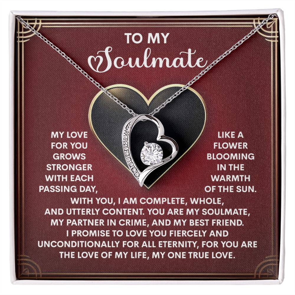 The Soulmate-One True Love - Forever Love Necklace, adorned with a heart-shaped pendant and a sparkling diamond, is elegantly set against a red backdrop. Its white gold finish beautifully symbolizes love and commitment to your soulmate.