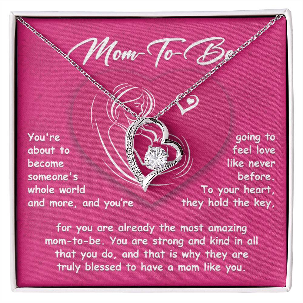 A To Mom To Be, Someone's Whole World Necklace with a heart-shaped pendant on a pink background featuring a loving message to a "mom-to-be" about the wonderful experience of motherhood.