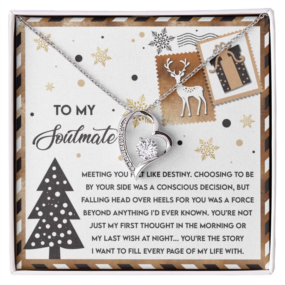 The Soulmate-Like Destiny - Forever Love Necklace, featuring a silver heart-shaped pendant with a delicate gold finish, is elegantly displayed on a decorative card. Adorned with winter-themed illustrations like snowflakes, a reindeer, and presents, it includes a heartfelt message about love.