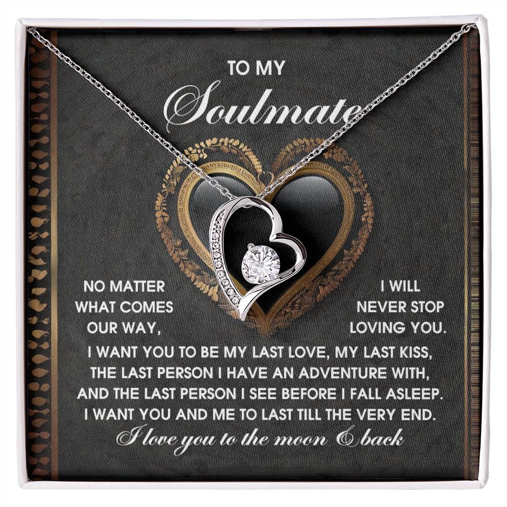 The Soulmate-The Very End - Forever Love Necklace boasts a heart-shaped pendant with a gold finish, adorned with cubic zirconia stones. It comes displayed on a card featuring a romantic message and decorative hearts, capturing the essence of eternal love.