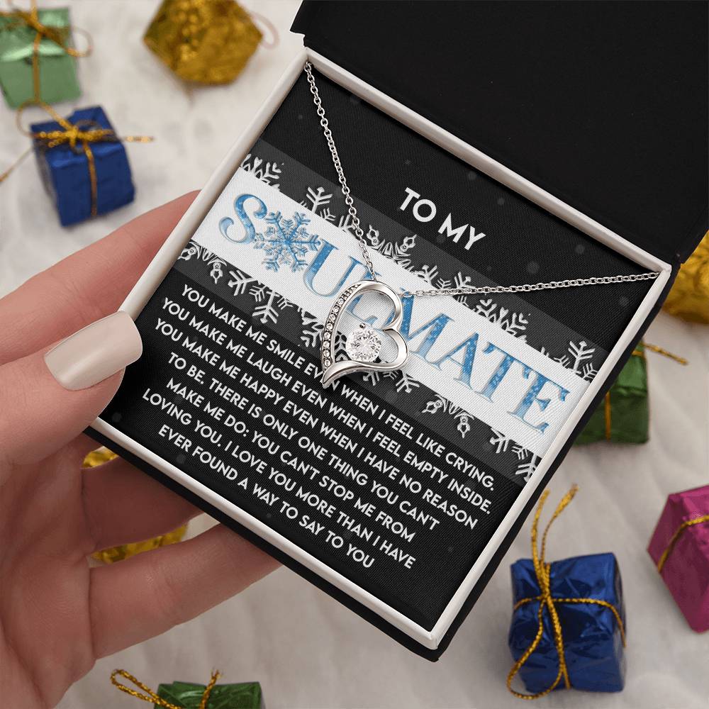 An open gift box reveals a Soulmate-Loving You - Forever Love Necklace with a heart-shaped pendant, glistening in a gold finish and adorned with CZ crystal. A card labeled "To My Soulmate" accompanies it, while small wrapped gifts linger in the background, adding to the romance.