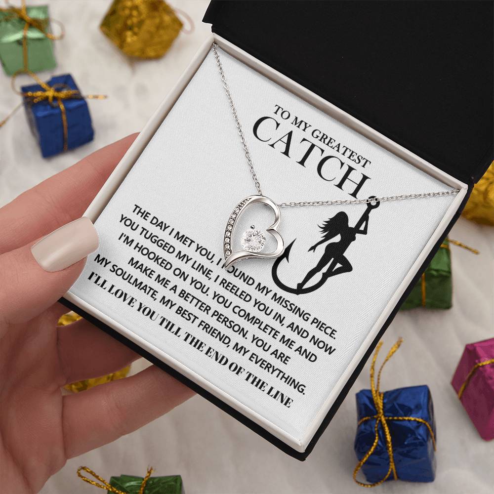 The Soulmate-Hooked On You - Forever Love Necklace has a heart-shaped pendant with a sparkling cubic zirconia stone and white gold finish. It's presented in a gift box with the message "To My Greatest Catch" in a fishing-themed design, nestled among wrapped presents.