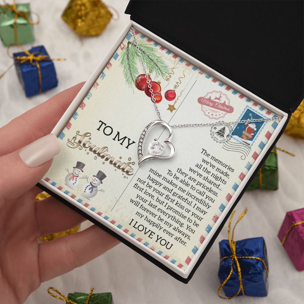 A person holds an open gift box unveiling the Soulmate-Last Everything - Forever Love Necklace, featuring a dazzling heart-shaped CZ crystal with a white gold finish. The box includes a message card decorated with charming snowmen, Christmas trees, and stamps, making it an ideal gift for the holiday season.
