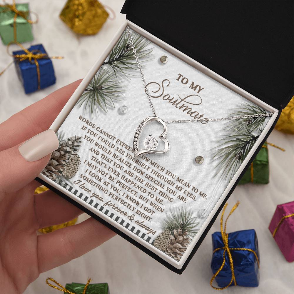 A person holds an open gift box containing the Soulmate-Perfectly Right - Forever Love Necklace with a gold finish, accompanied by an insert card featuring a message to a soulmate. Small wrapped presents surround the box.