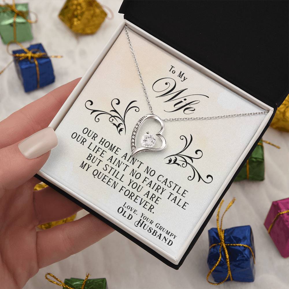 A hand holding an open gift box with a gold-finish To My Wife, You Are My Queen Forever - Forever Love Necklace from ShineOn Fulfillment and a heartfelt message to a wife from her husband.
