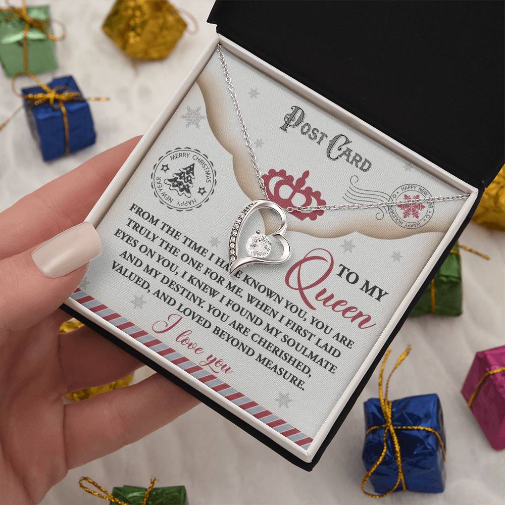 A Soulmate-The One - Forever Love Necklace displayed in a black box, highlighted by a heartfelt message on a card. It is embellished with a shimmering CZ crystal and gold finish, set against an array of small, wrapped gifts.