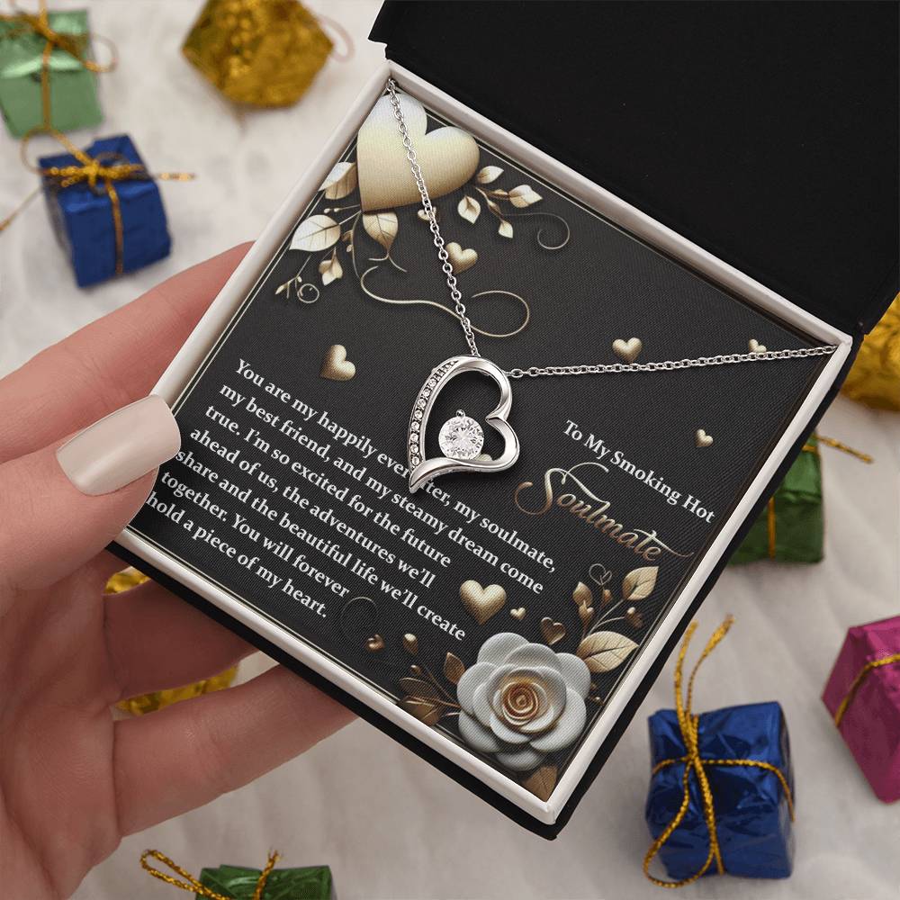 A hand presents an open jewelry box showcasing the Soulmate-The Future - Forever Love Necklace, featuring a heart-shaped pendant with radiant cubic zirconia and a chic gold finish. Inside the box is a romantic message, encircled by small, wrapped gifts.