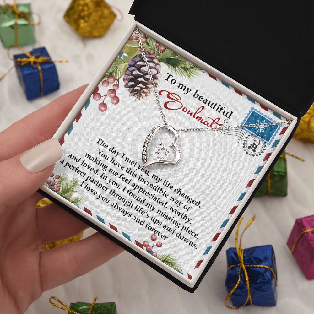 A heart-shaped necklace with a CZ crystal and gold finish is elegantly displayed in an open box. Inside, a card addressed to "My beautiful soulmate" features decorative pinecones and berries, making it the perfect choice for the Soulmate-Perfect Partner - Forever Love Necklace.