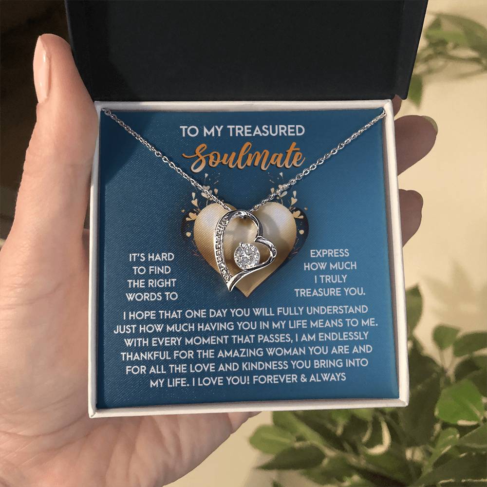 A person holds a gift box with the Soulmate-In My Life - Forever Love Necklace, featuring a heart pendant and an affectionate message for their soulmate. The elegant design, with a white gold finish and sparkling CZ crystal, embodies eternal devotion.