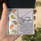 A hand holding an open box unveils the stunning Daughter-Biggest Fan - Forever Love Necklace, featuring a heart-shaped pendant with a white gold finish, nestled beside a heartfelt message card addressed to a daughter.