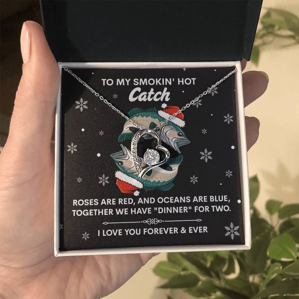 A hand holds a "Soulmate-Oceans Are Blue - Forever Love Necklace" in a gift box featuring two fish shapes, a heart, and a cubic zirconia stone. The box reads, "To my smokin' hot catch," accompanied by a heartfelt poem.