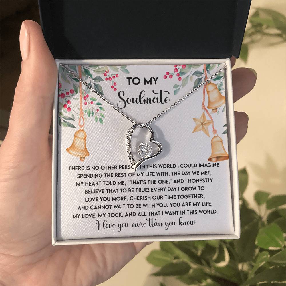 A hand holds a jewelry box containing the Soulmate-Be With You - Forever Love Necklace, featuring a heart-shaped pendant adorned with a shimmering CZ crystal. The box displays a heartfelt message for a soulmate, adding to the necklace’s special significance.