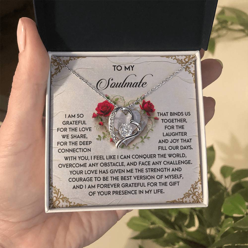 A hand holds an open jewelry box containing the Soulmate-Our Days - Forever Love Necklace, a heart-shaped design with roses, dazzling CZ crystal, and white gold finish. Inside the lid is a heartfelt message to a soulmate expressing gratitude and love.