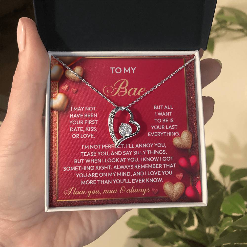 A hand presents an open jewelry box revealing the Soulmate-On My Mind - Forever Love Necklace, a heart-shaped pendant with a white gold finish and adorned with CZ crystals. It rests on a red card, delivering a romantic message to your loved one.