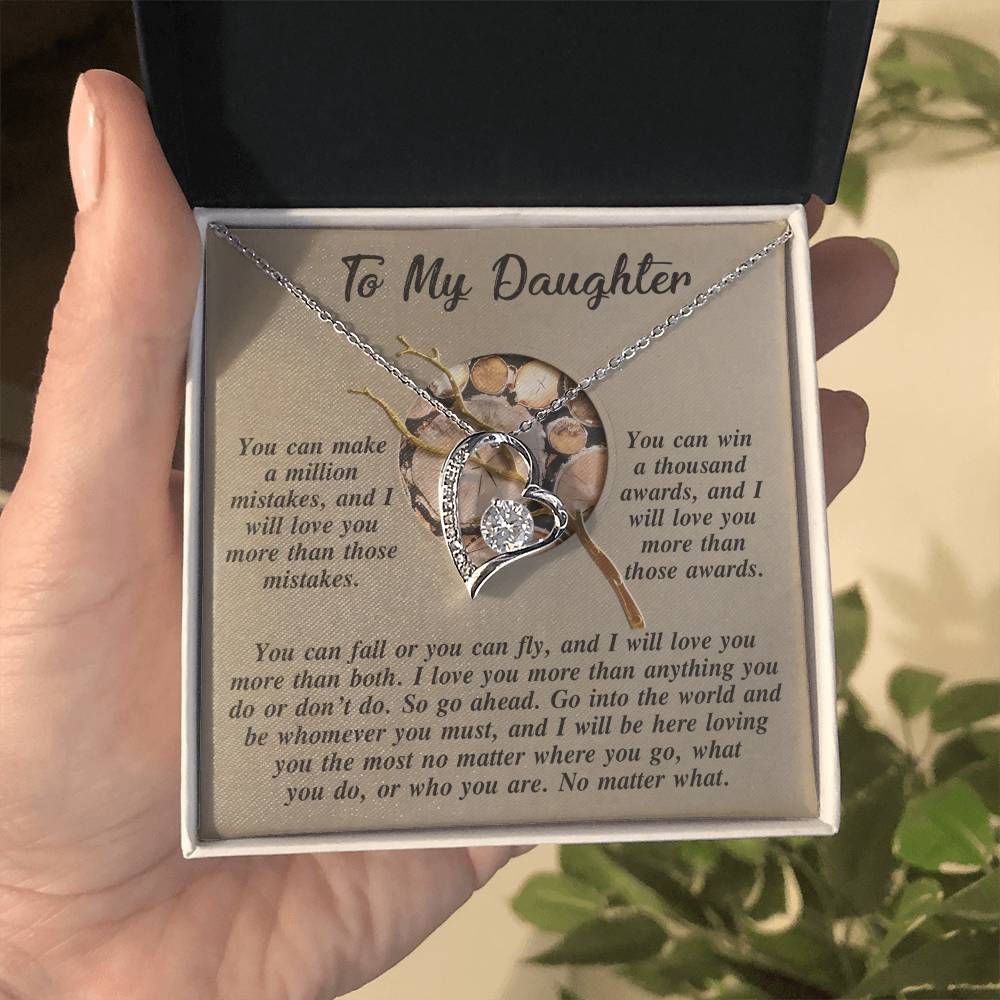 The Daughter-A Thousand Awards - Forever Love Necklace, a silver heart pendant with a white gold finish, is elegantly displayed in an open jewelry box. It includes an inscription that reads "To My Daughter," accompanied by an inspirational message, enhancing the elegance and sentiment of this exquisite gift.