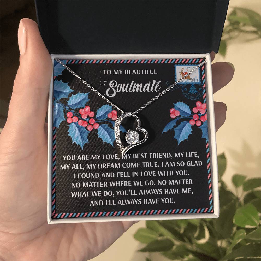 A hand holds an open gift box containing a heart-shaped Soulmate-Fell In Love - Forever Love Necklace. Inside the box is a decorative card with a heartfelt message.