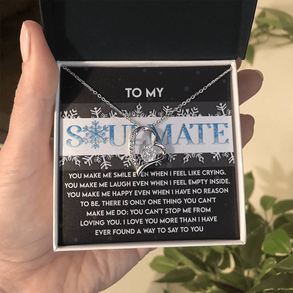 A hand unveils a gift box to reveal the Soulmate-Loving You - Forever Love Necklace, showcasing a heart-shaped pendant with a sparkling cubic zirconia stone. The box displays "TO MY SOULMATE" in elegant script, accompanied by a heartfelt message beneath, all exquisitely presented in a white gold finish.