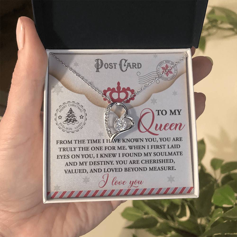 A hand presents a gift box unveiling the Soulmate-The One - Forever Love Necklace, shimmering with a gold finish. Inside, the card says, "To my Queen" along with a romantic message. The heart-shaped pendant sparkles magnificently with CZ crystal brilliance.