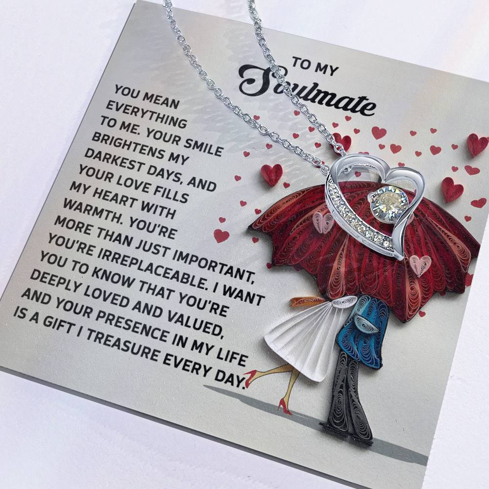 The Soulmate-Deeply Loved - Forever Love Necklace showcases a heart pendant on a card with a romantic couple under an umbrella with hearts illustration, adorned with a sparkling CZ crystal in white gold finish.