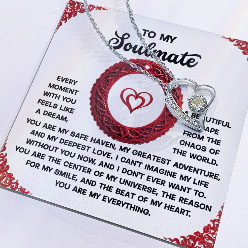 The Soulmate-Like A Dream - Forever Love Necklace is a silver heart-shaped piece with a sparkling cubic zirconia stone finished in white gold. It rests on a card with a romantic message for your soulmate, framed by red designs and featuring an elegant red heart motif.