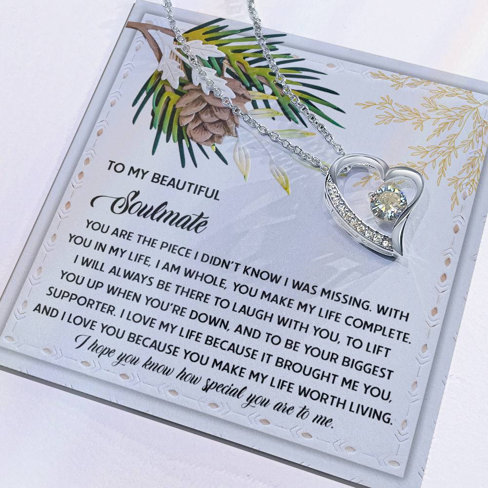 The Soulmate-Biggest Supporter - Forever Love Necklace, featuring a heart-shaped design with a gold finish, is set against a card decorated with floral and pinecone illustrations and carries a heartfelt message to a soulmate.