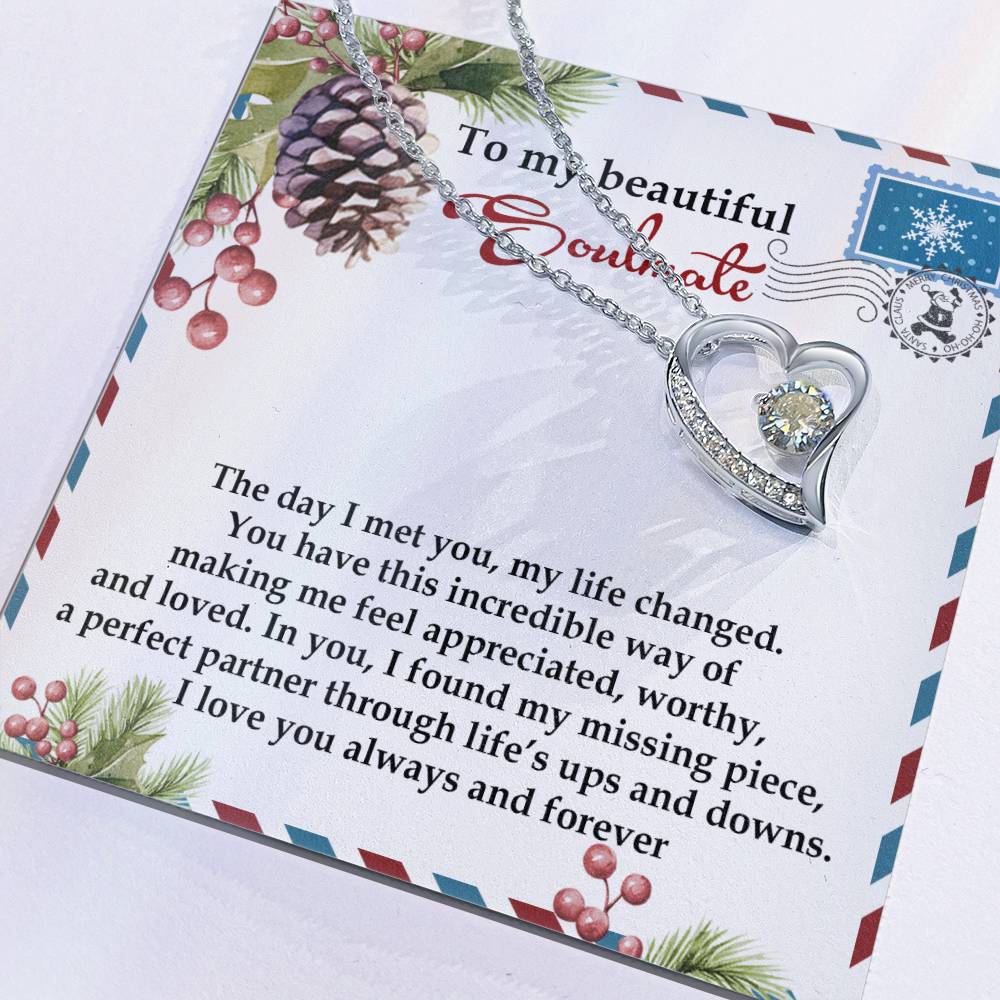 The Soulmate-Perfect Partner - Forever Love Necklace features a heart shape adorned with a CZ crystal and a gold finish, beautifully displayed on a card with a romantic message, complete with the enchanting design of pinecones and berries.