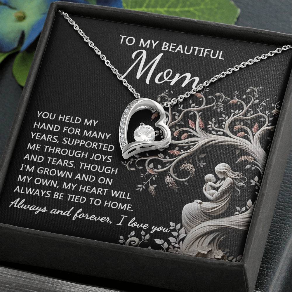 A personalized gift, the "To Mom, On My Own - Forever Love Necklace" features a heart-shaped pendant with a cubic zirconia stone, elegantly presented on a card that reads, "To My Beautiful Mom," alongside a heartfelt message about love and support.