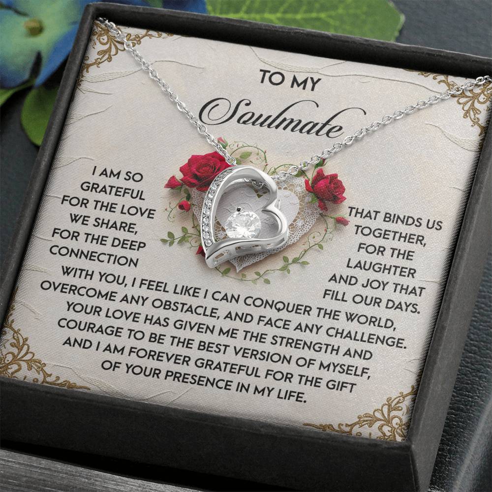 The Soulmate-Our Days - Forever Love Necklace showcases a heart-shaped design with a dazzling CZ crystal, elegantly presented in a box. The backdrop features gratitude text to a soulmate, adorned with roses and a decorative border beneath its white gold finish.