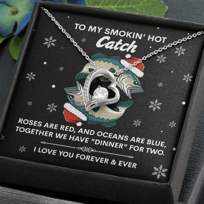 The Soulmate-Oceans Are Blue - Forever Love Necklace, featuring a heart pendant and cubic zirconia stone, is showcased in an open box. The backdrop has fish and holiday graphics with the text: "To my smokin' hot catch... I love you forever & ever.