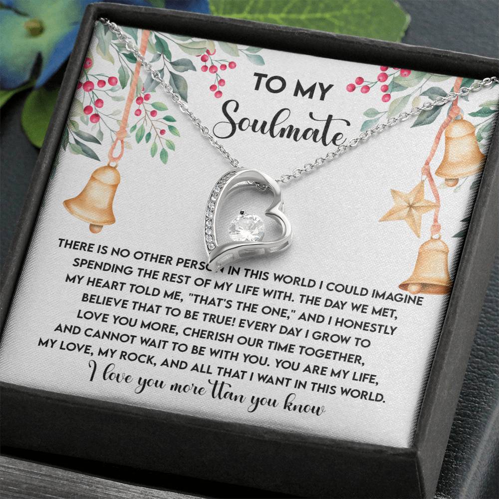 The "Soulmate-Be With You - Forever Love Necklace," showcasing a heart-shaped pendant embellished with sparkling cubic zirconia stones, arrives beautifully packaged in a gift box containing a heartfelt message to your soulmate, surrounded by delicate floral and bell decorations.