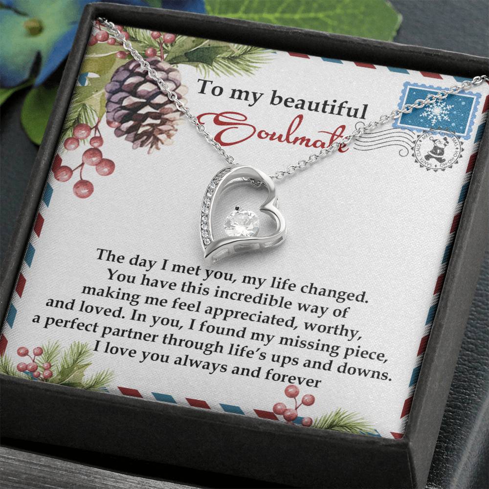 The Soulmate-Perfect Partner - Forever Love Necklace, featuring a heart-shaped design and gold finish, is elegantly set against a card decorated with floral and pinecone motifs. Accentuated by a sparkling CZ crystal, it includes a heartfelt message ideal for your soulmate.