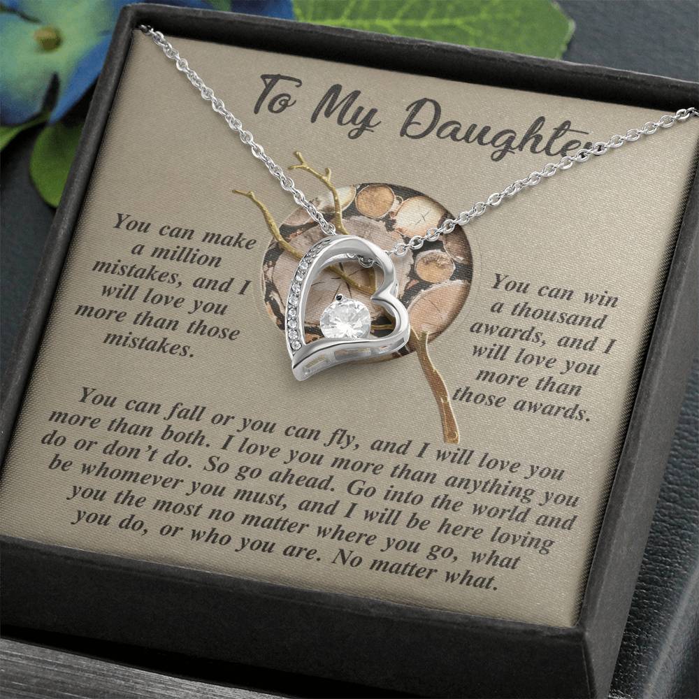 The Daughter-A Thousand Awards - Forever Love Necklace, featuring a heart-shaped design with a central cubic zirconia stone, is elegantly showcased in a box. Its gold finish enhances its charm, complemented by an inspirational message for a daughter in the background.