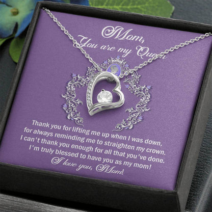 The "To Mom, Belongs To Me - Forever Love Necklace," featuring a silver heart-shaped pendant adorned with a clear cubic zirconia gem, is beautifully presented on a purple card inside an elegant box. The card bears a touching message of gratitude to a mother, concluding with "I love you, Mom!" This necklace makes the perfect personalized gift for any special occasion.