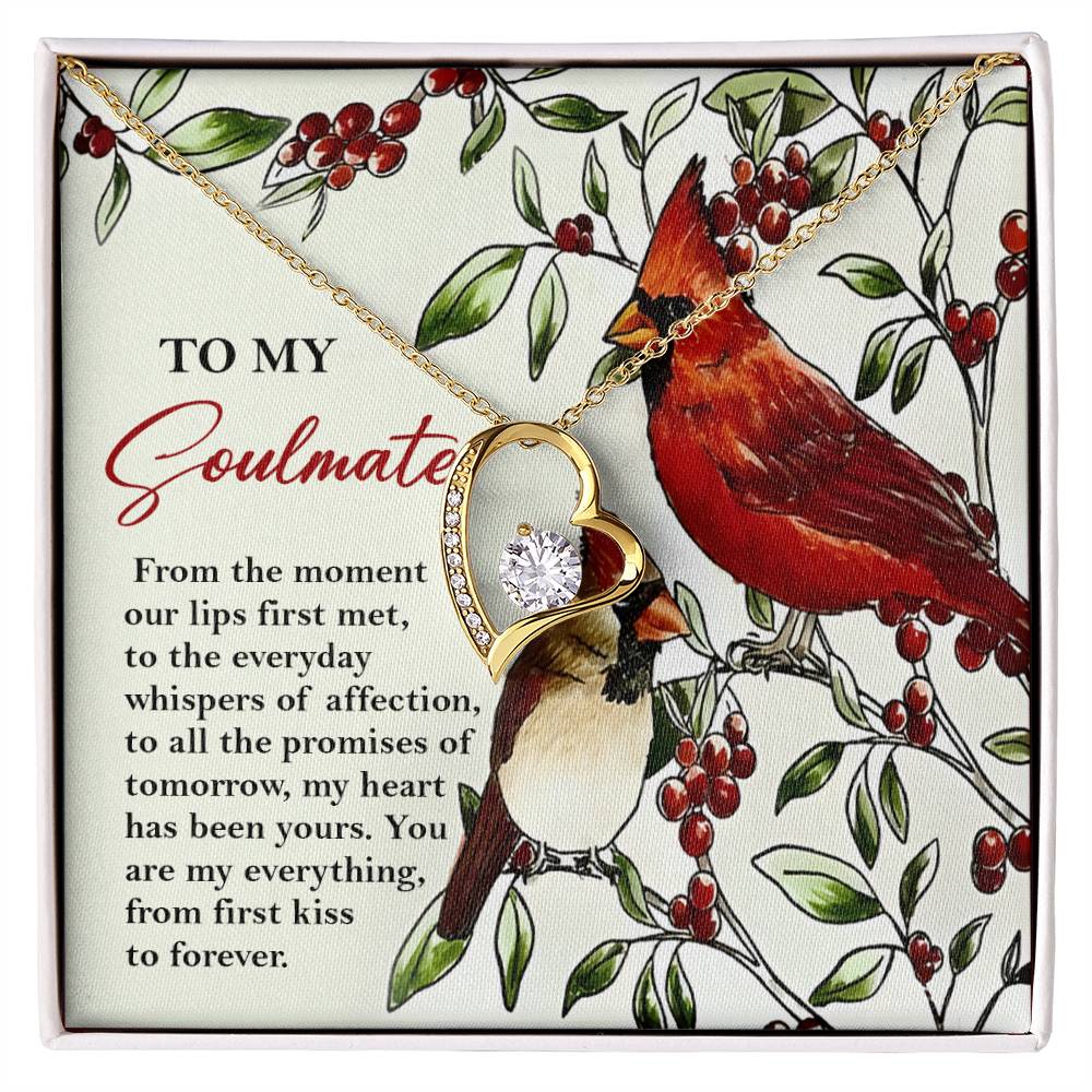 The Soulmate-First Kiss - Forever Love Necklace showcases a heart pendant with a stunning gold finish and shimmering cubic zirconia crystals, beautifully presented on a card featuring two birds and an affectionate message.