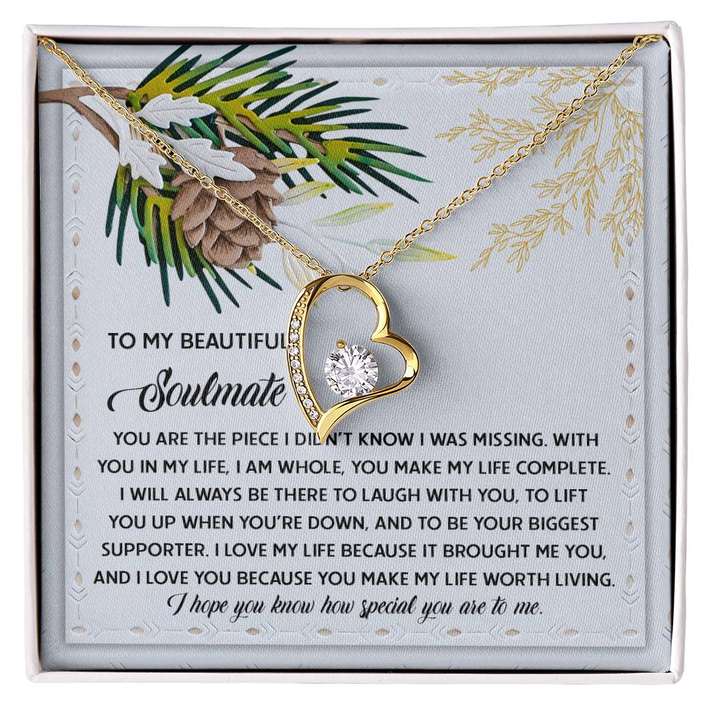 The Soulmate-Biggest Supporter - Forever Love Necklace showcases a heart-shaped pendant in gold, elegantly adorned with a radiant cubic zirconia stone. It is presented on a box featuring a heartfelt message, enhanced by delightful pine cone and branch illustrations, all beautifully finished with white gold.