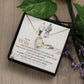 A ShineOn Fulfillment To My Wife, I Just Want To Be Your Last Everything - Forever Love Necklace with a heart-shaped pendant inside a gift box with a loving message for a wife, displayed on a wooden surface with green leaves and purple flowers.