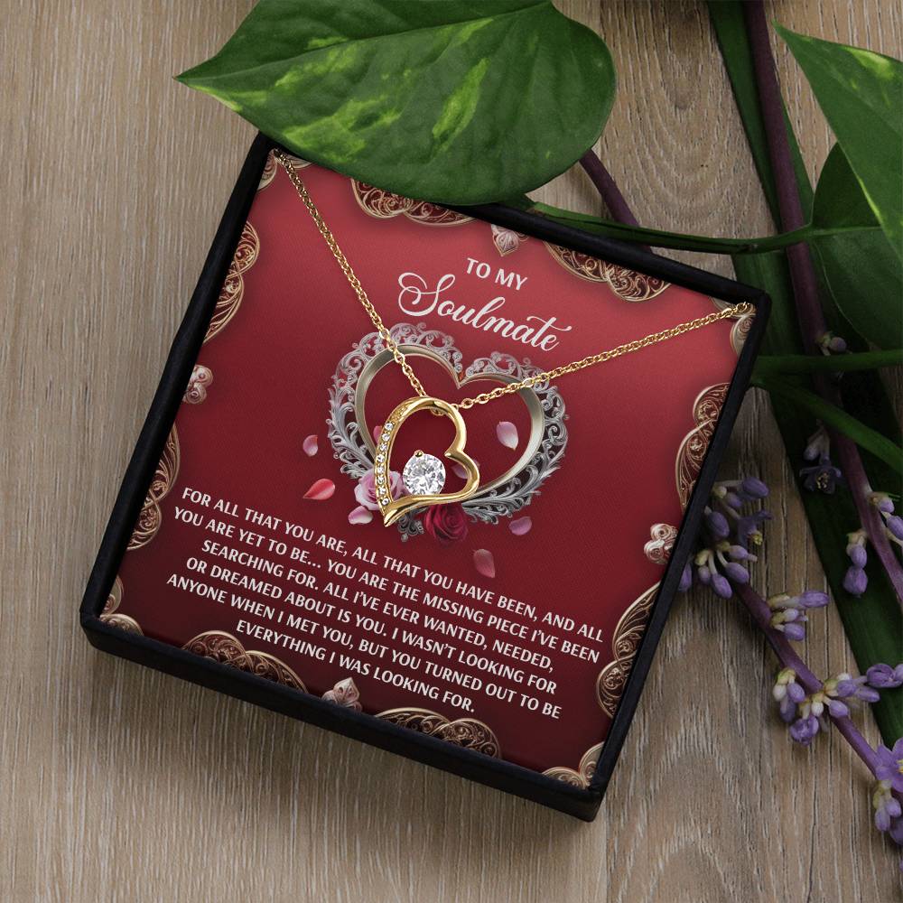 The Soulmate-I Met You - Forever Love Necklace features a heart pendant with a stunning 6.5mm CZ crystal and white gold finish, presented in an ornate gift box adorned with floral designs and a love message for your soulmate, alongside partially visible flowers.