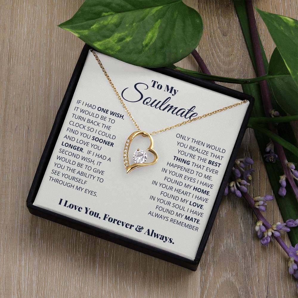 A "To My Soulmate, I Love You, Forever & Always" Necklace by ShineOn Fulfillment with a gold finish and a cubic zirconia heart pendant presented in a box with a romantic message to a soulmate, placed on a wooden surface with purple flowers.