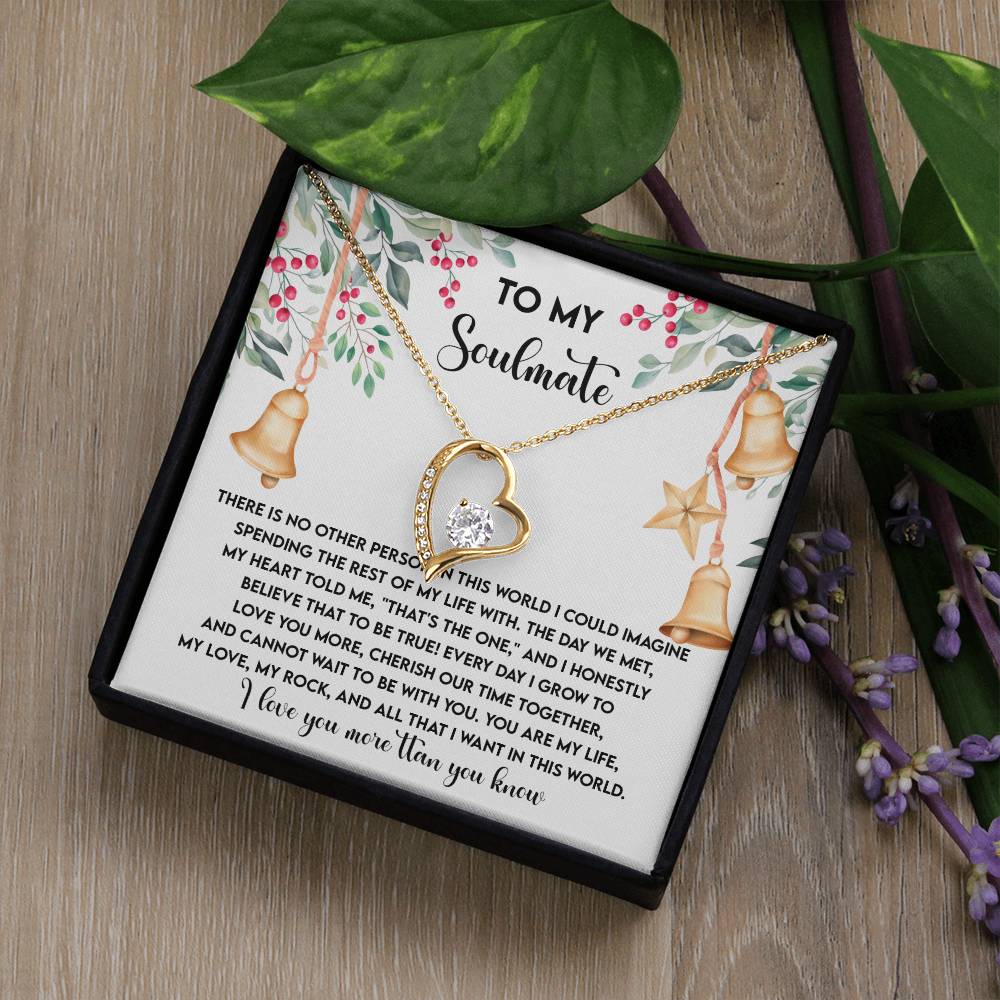 The Soulmate-Be With You - Forever Love Necklace features a heart-shaped pendant with a luxurious gold finish, embellished with a diamond and CZ crystal. It arrives in an elegant gift box, with the lid displaying a heartfelt message to your soulmate framed by floral borders and adorned with printed bells.