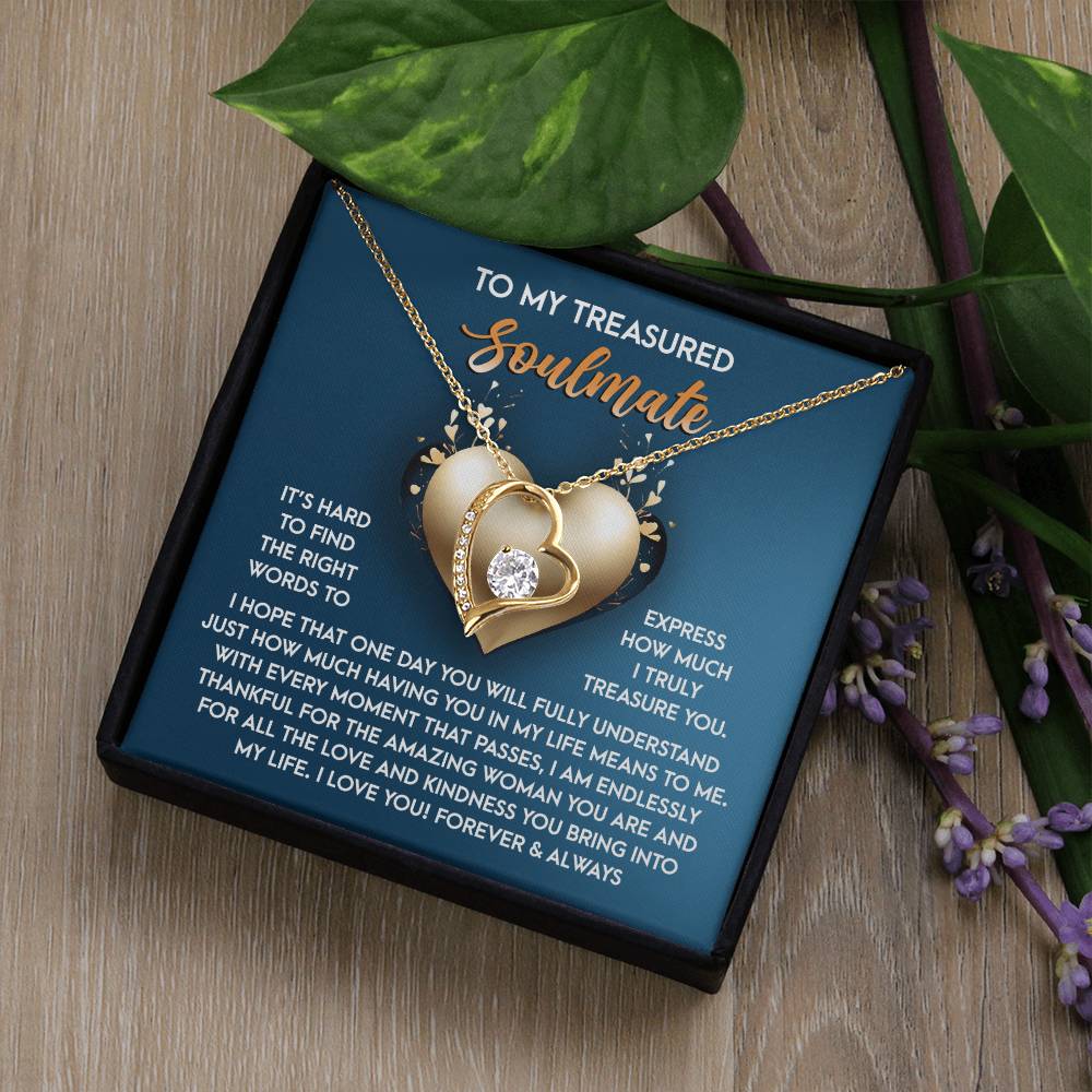 The Soulmate-In My Life - Forever Love Necklace showcases a gold heart with a diamond, set on a black box. The card says "To my treasured soulmate," expressing love and appreciation. With green leaves and small flowers, it dazzles in its delicate white gold finish.