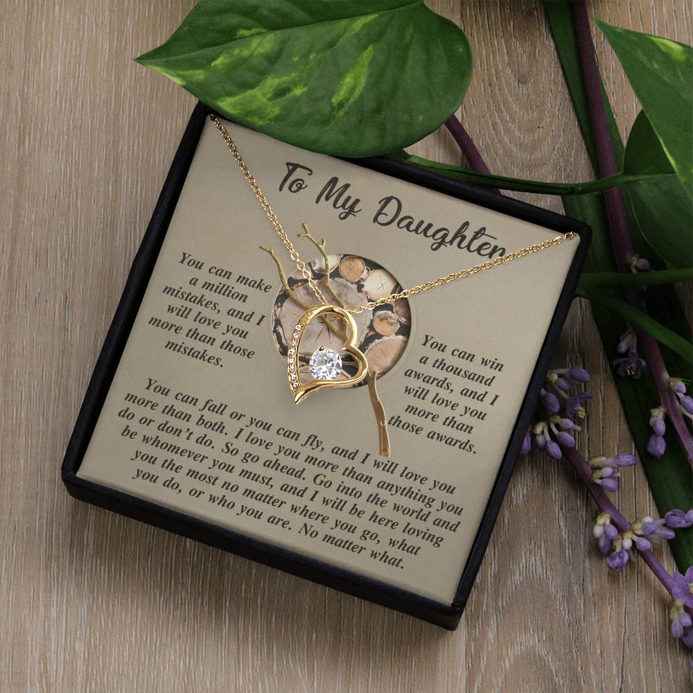 The Daughter-A Thousand Awards - Forever Love Necklace, featuring a heart-shaped pendant embellished with a sparkling cubic zirconia crystal, is elegantly displayed on a "To My Daughter" message card amidst lush green leaves.