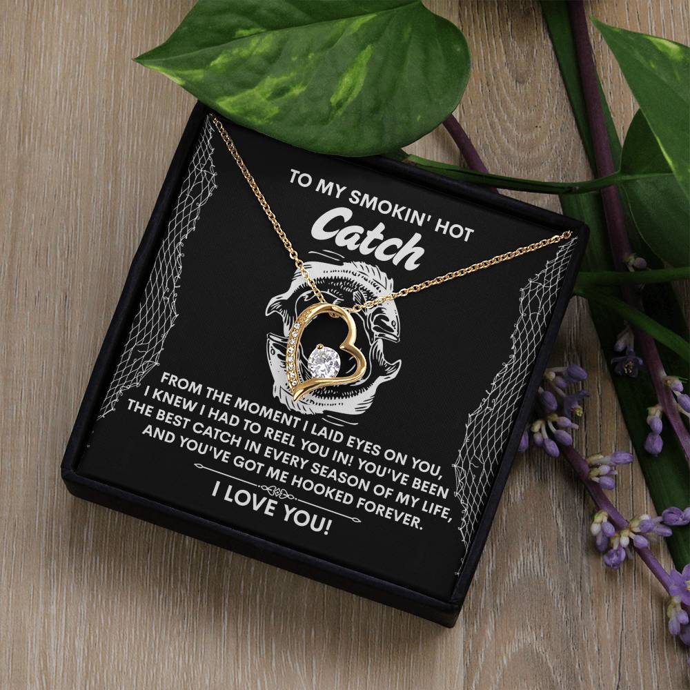 The Soulmate-Got Me Hooked - Forever Love Necklace has a heart-shaped pendant with a CZ crystal and white gold finish, resting beautifully on a black gift box with a romantic message, surrounded by leaves and flowers.