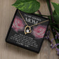 The "To Bonus Mom, My Chosen Mom - Forever Love Necklace" is an elegant heart-shaped piece featuring a central jewel. It comes in a presentation box with a heartfelt message for your chosen mother, alongside two pink rose images and green foliage in the background. This sophisticated Mother's Day gift is available in either white gold or yellow gold finish.
