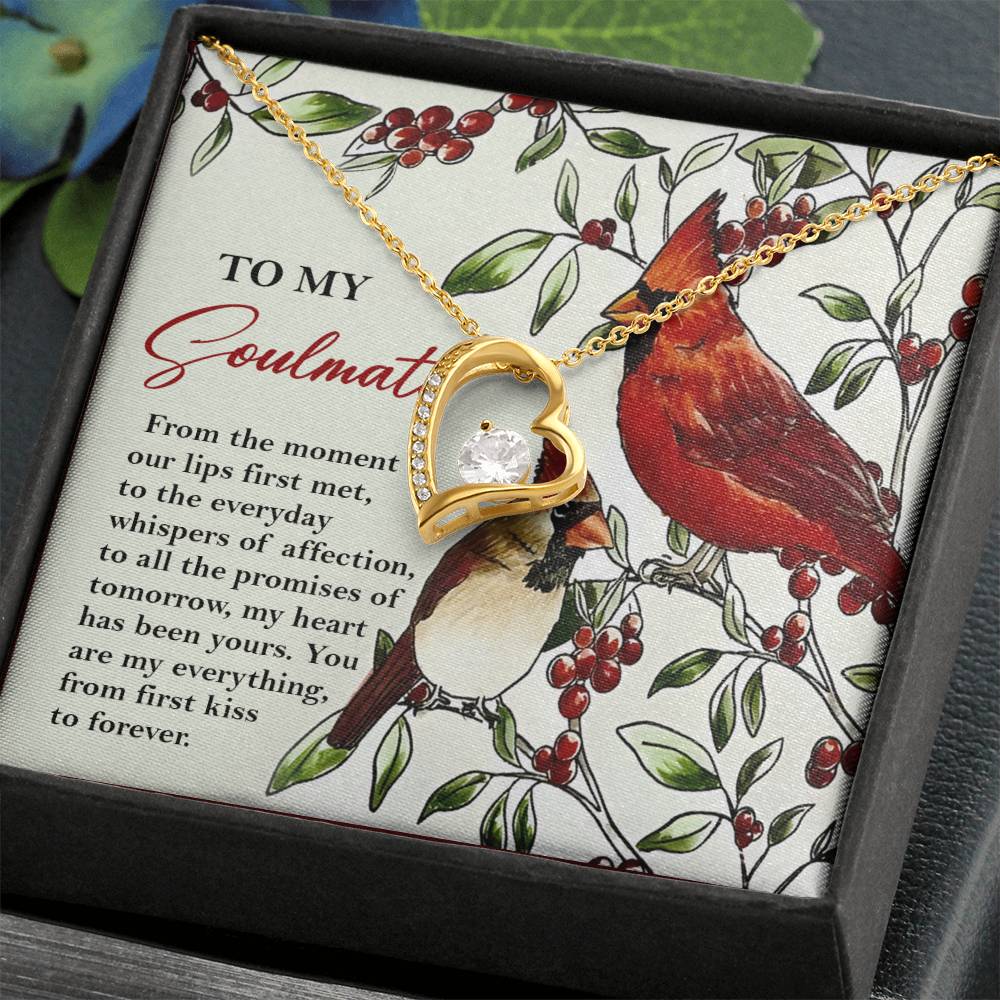 The Soulmate-First Kiss - Forever Love Necklace showcases a heart-shaped pendant featuring a sparkling CZ crystal. It is elegantly displayed on a card with romantic text and an illustration of two birds, while its gold finish adds a timeless touch to this heartfelt keepsake.