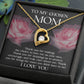The "To Bonus Mom, My Chosen Mom - Forever Love Necklace" features a gold heart-shaped pendant with a single clear gem at its center. It is elegantly presented in a black box that includes an appreciative message for a "chosen mom," and the card background adorned with pink roses makes it an ideal Mother's Day gift. This necklace is available in both white gold and yellow gold finishes.
