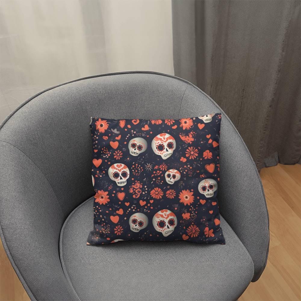 On a gray chair, the Day of the Dead Mexican Skull Pillow stands out with its sugar skull designs adorned with skulls, hearts, and flowers on a dark background—ideal for infusing a bit of goth flair into your home decor.