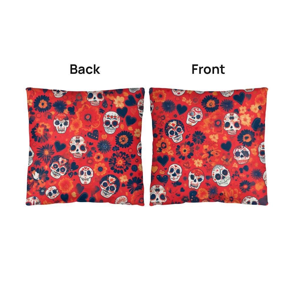 These two decorative cushions are ideal for gothic home decor, featuring vibrant red covers embellished with skulls and flowers. One cushion showcases the intricate skull art on the front, while the other captivates with its Day of the Dead Mexican Skull Pillow design.