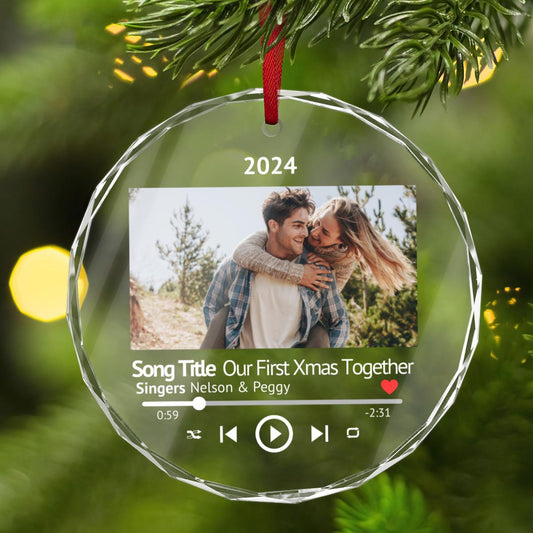 A Custom First Christmas Together CRYSTAL GLASS Music Player Ornament elegantly hangs on a tree branch, celebrating "Our First Xmas Together" with musical features and the year 2024. This personalized photo keepsake gift for new couples beautifully captures the moment, transforming it into a unique Xmas tree decor piece to cherish forever.