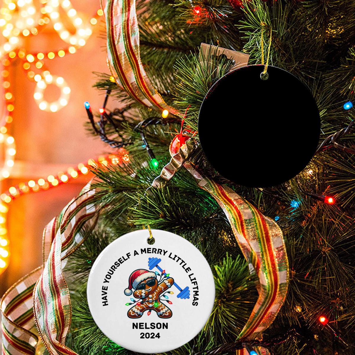 A Christmas tree adorned with decorative lights and ribbons showcases the unique Merry Liftmas Weightlifting Ceramic Ornament. Nearby, a white ornament featuring a cartoon character and the text "Have Yourself a Merry Little XMAS Nelson 2024" hangs prominently, making it the perfect gym Christmas gift for any fitness enthusiast.